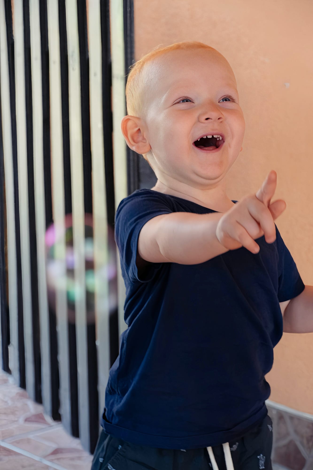 Lachender kleiner Junge zeigt auf eine Seifenblase